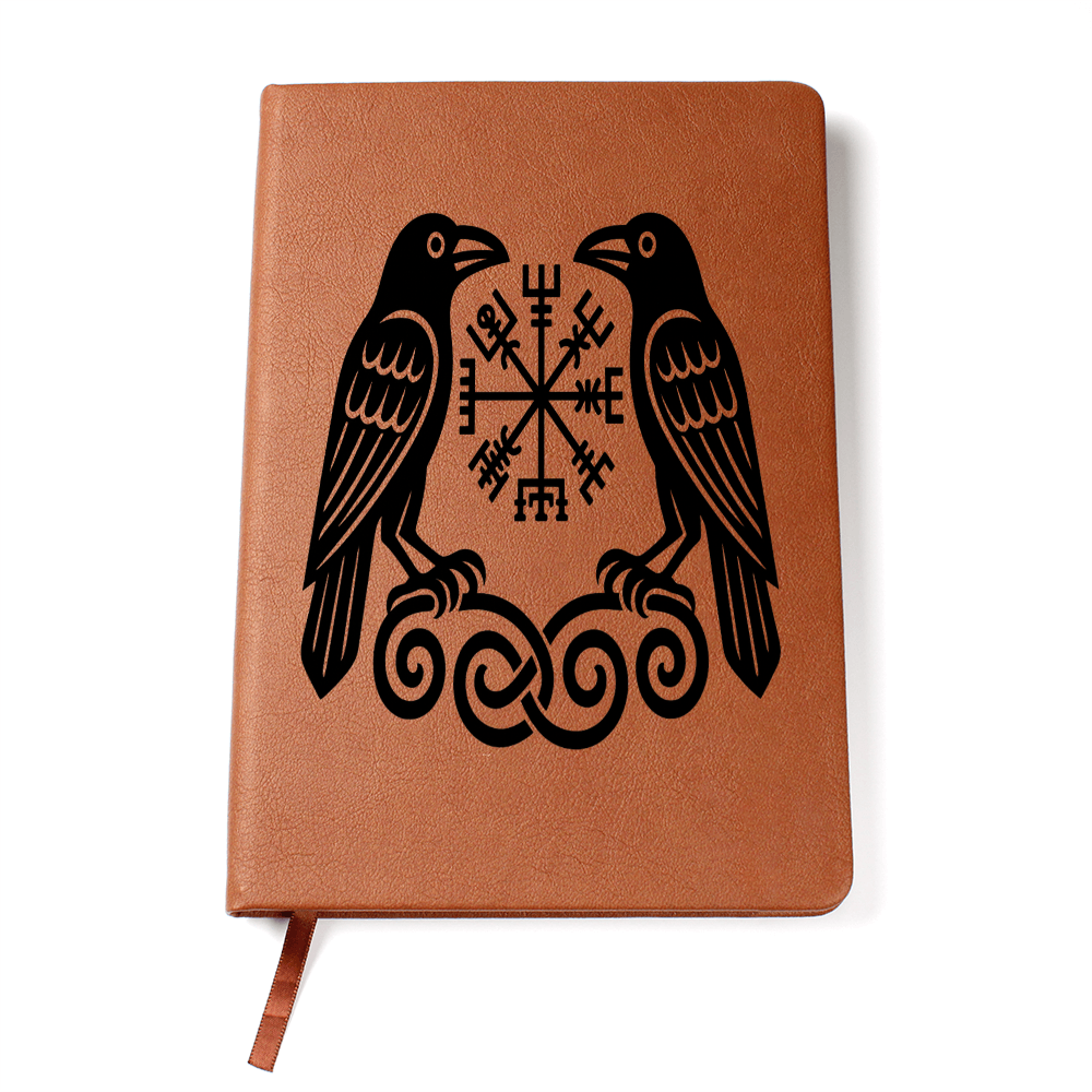 Tan vegan leather A5 journal on white background featuring two black Norse ravens facing a Vegvisir rune compass atop knotwork, ribbon bookmark visible.