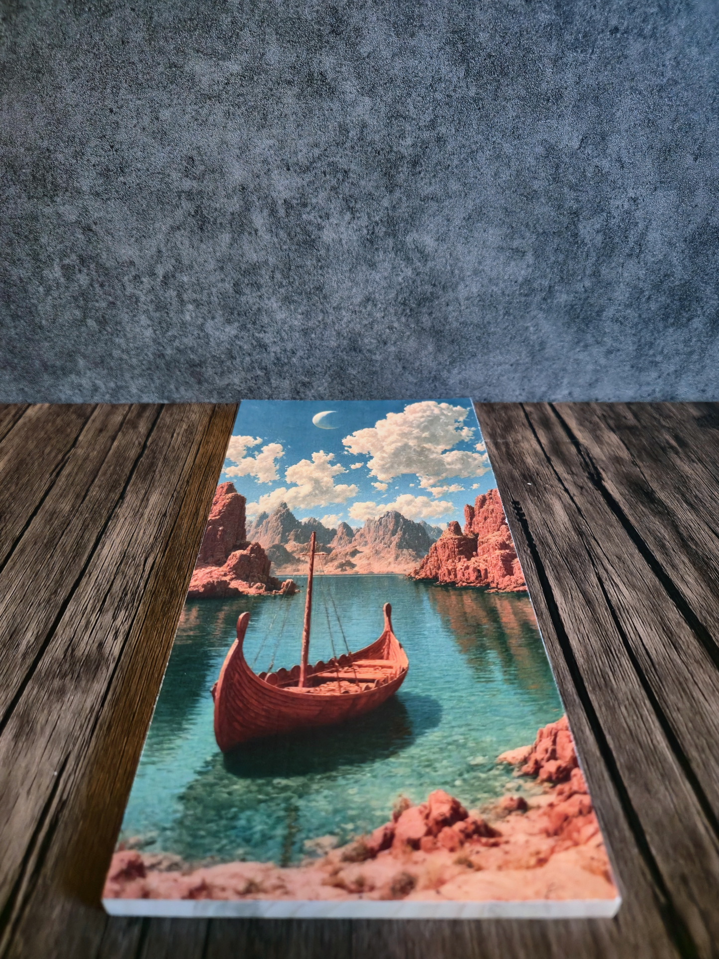 Scene of Viking ship artwork on wooden table and grey background, artwork made onto a piece of hardwood.