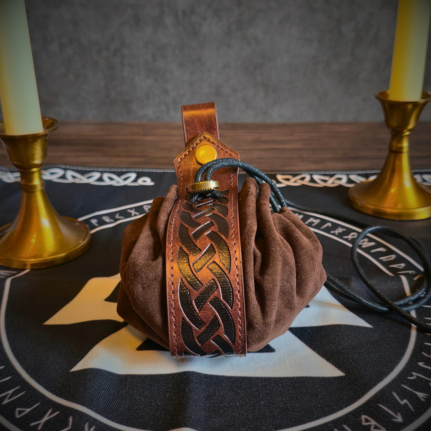 Brown leather bag with intricate designs on a table with candles and a star pattern.