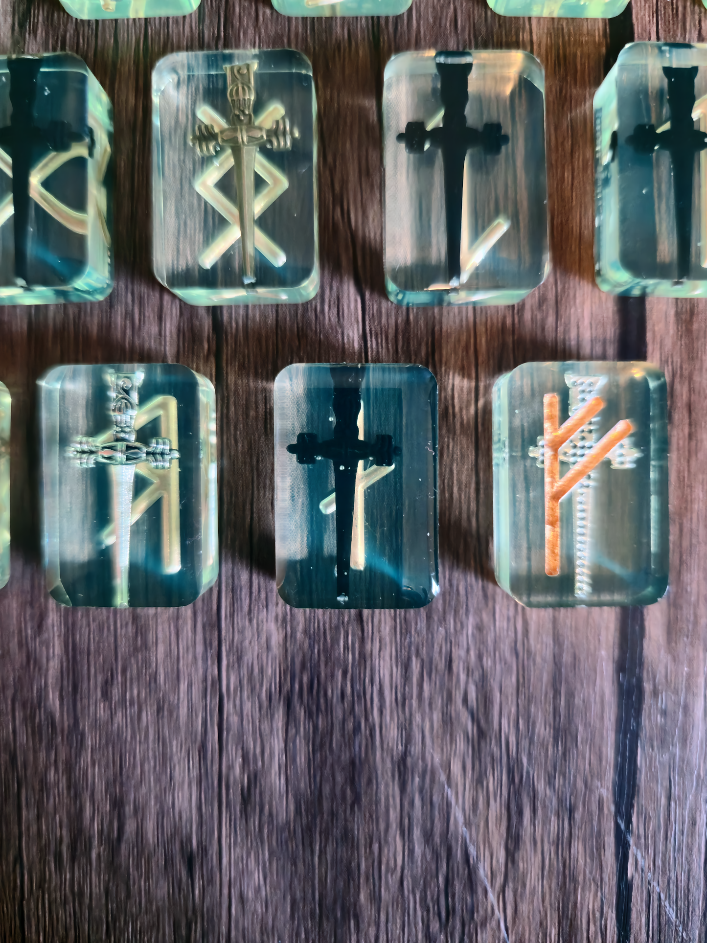 Up-close view on runestone with black sword with gold rune symbols on wooden table.