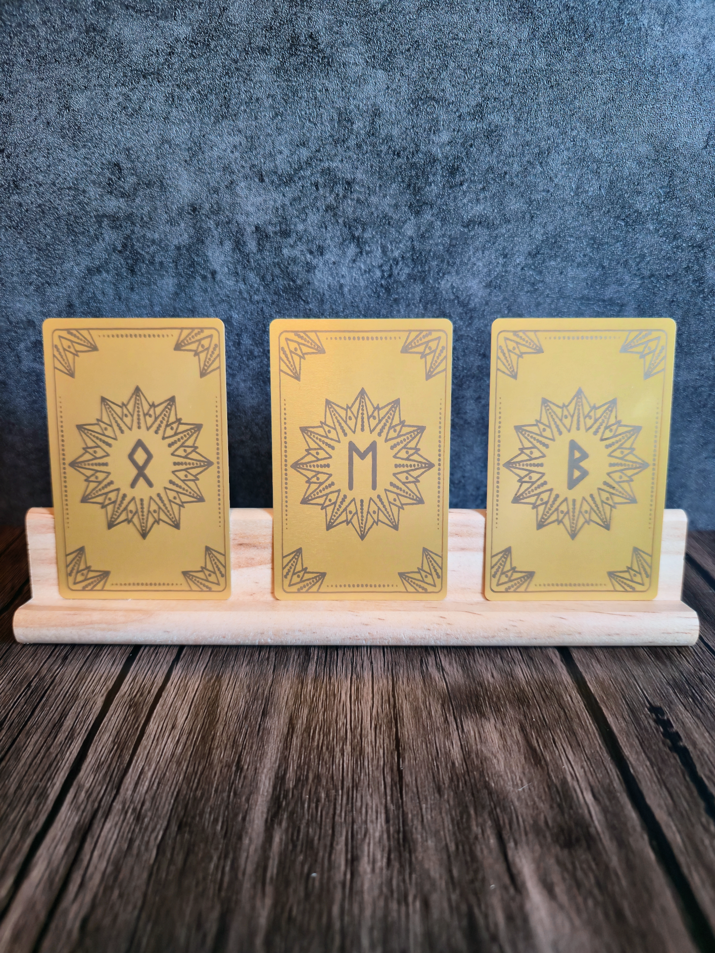 Three yellow cards with star designs and rune symbols on a stand against a blue textured background
