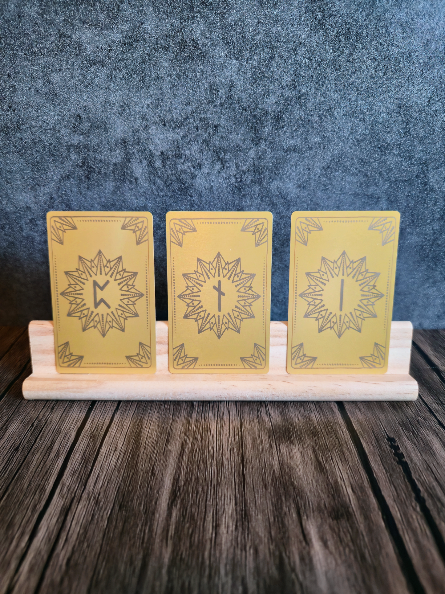 Three yellow cards with star designs and Viking symbols on a wooden stand against a blue textured background on a wooden table.