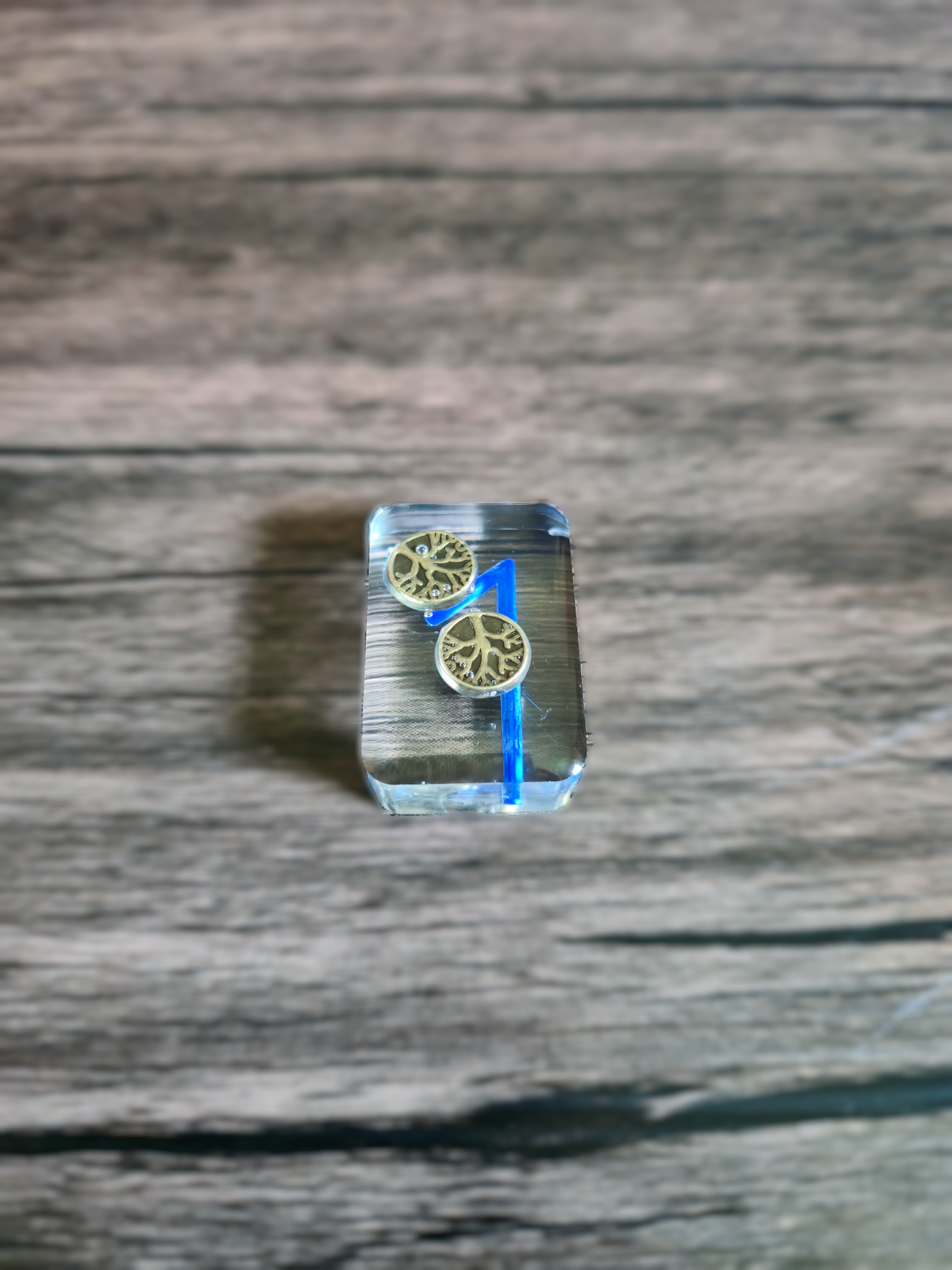 Clear resin block with gold circular designs on a wooden surface
