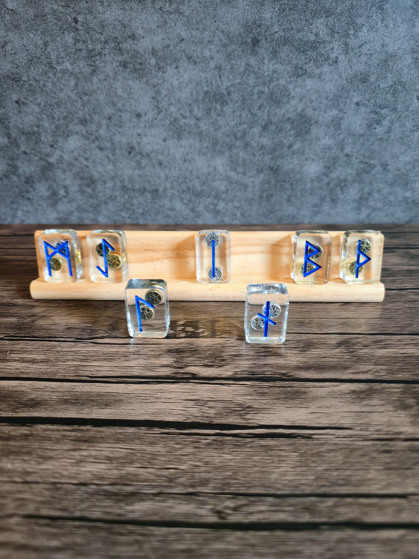 Set of clear runes with blue symbols on a wooden stand against a gray background