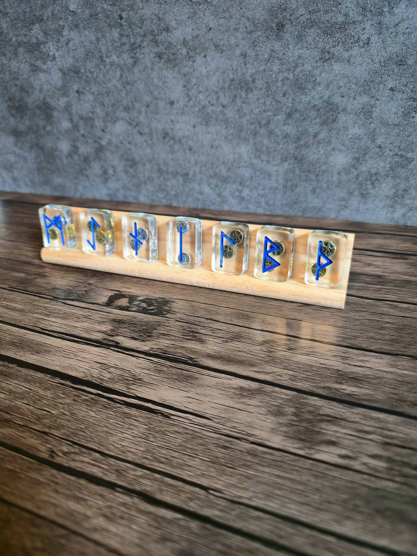 Decorative set of Norse runic stones on a wooden stand against a gray background