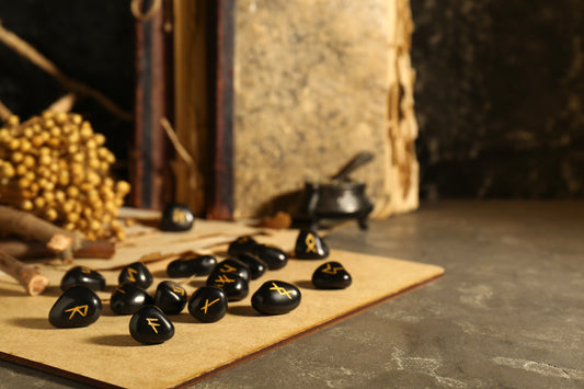black rock runestones spread out on a table with a stone structure in the background