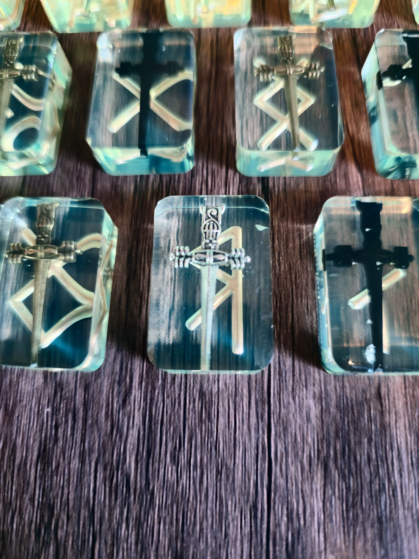 Up close view of runestone with silver sword and gold Viking symbol on wooden table.