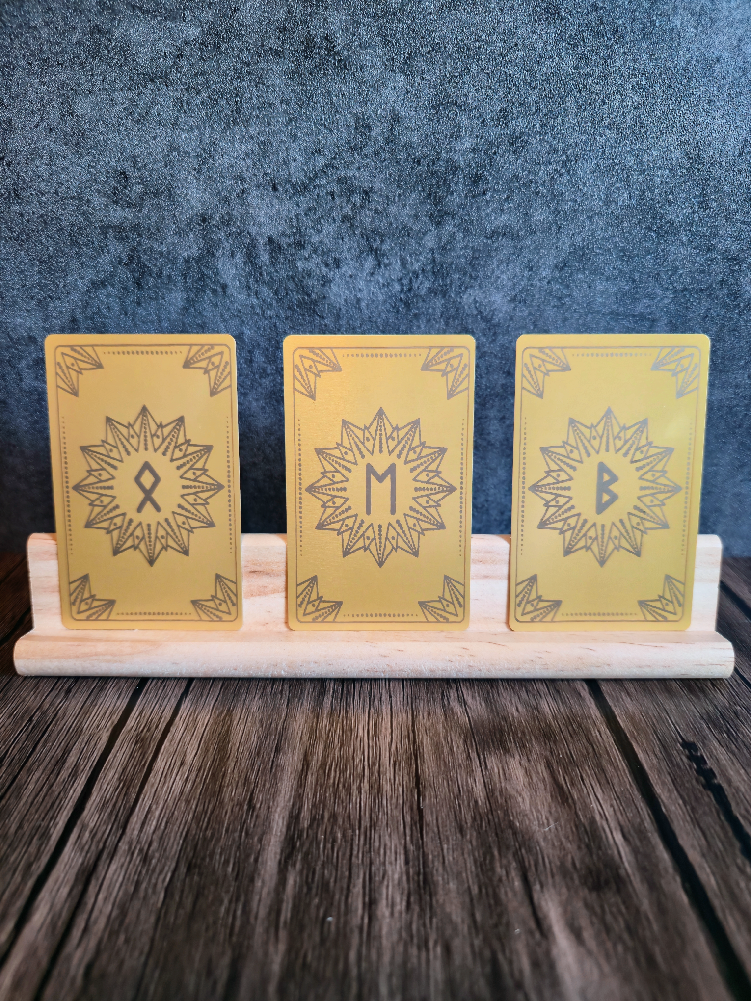Three yellow cards with star designs and rune symbols on a stand against a blue textured background
