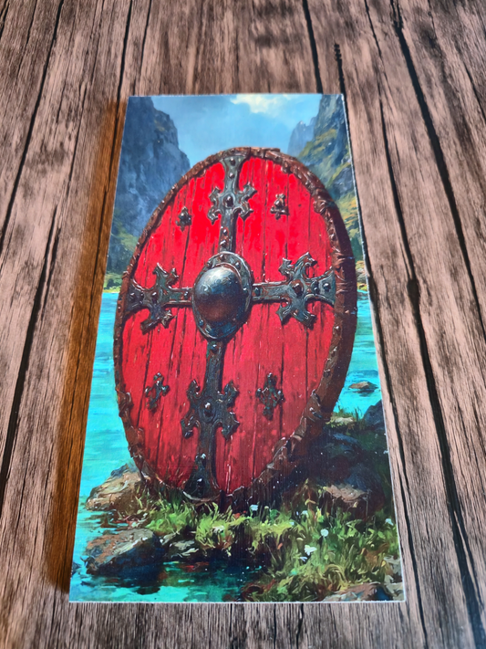 Red shield with decorative patterns on a scenic background, placed on a wooden surface.