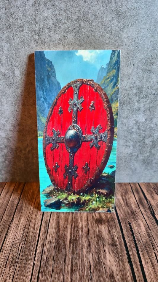 Red Viking shield with decorative patterns on a mountainous landscape background