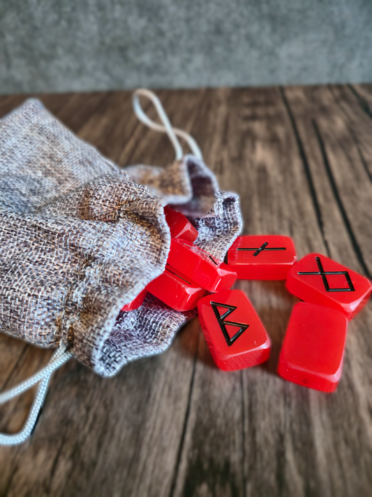 red runes with black symbols spread on a wood table with grey background